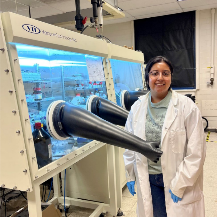 female scientist standing in front of a glove box